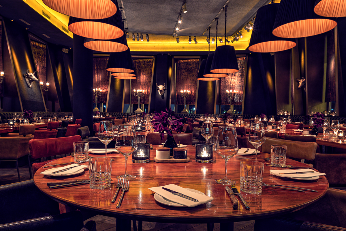 Innenbereich mit zahlreichen, gedeckten Tischen, Runder Tisch im Vordergrund im Steakhouse, Restaurant und Bar Rocca 800°C im Düsseldorfer Medienhafen