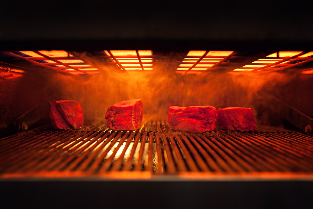 Fleisch wird im Grill zubereitet, Feuer, Dampf und Qualm