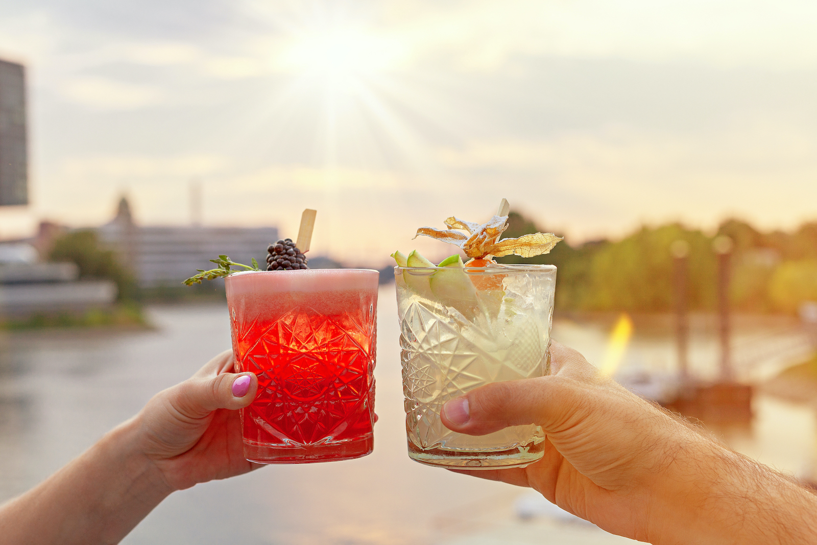 Zwei Personen stoßen auf der Terrasse mit Rheinblick im Restaurant Rocca 800°C mit Cocktails an