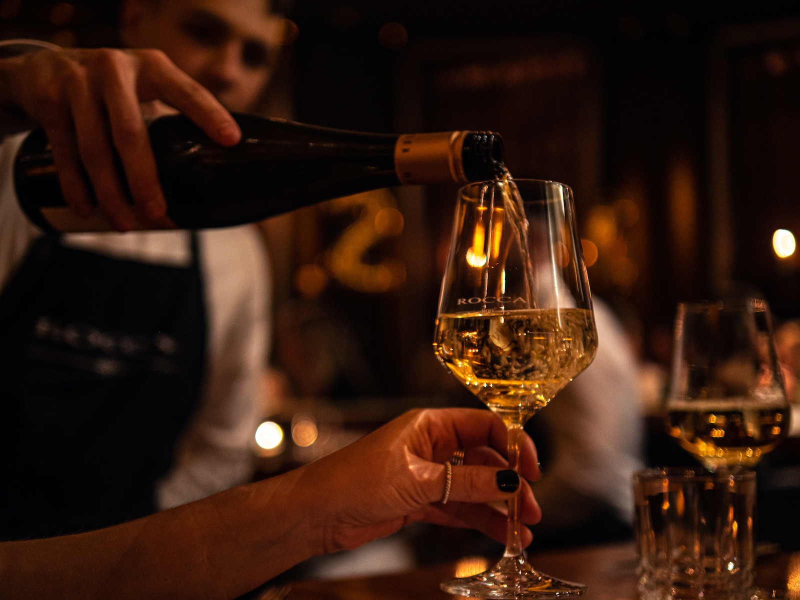 Kellner schenkt ein Glas Weißwein ein im Restaurant Rocca 800°C in Düsseldorf