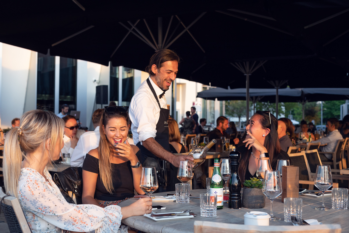 Kellner schenkt im Außenbereich Wein aus im Restaurant Rocca 800°C im Düsseldorfer Medienhafen